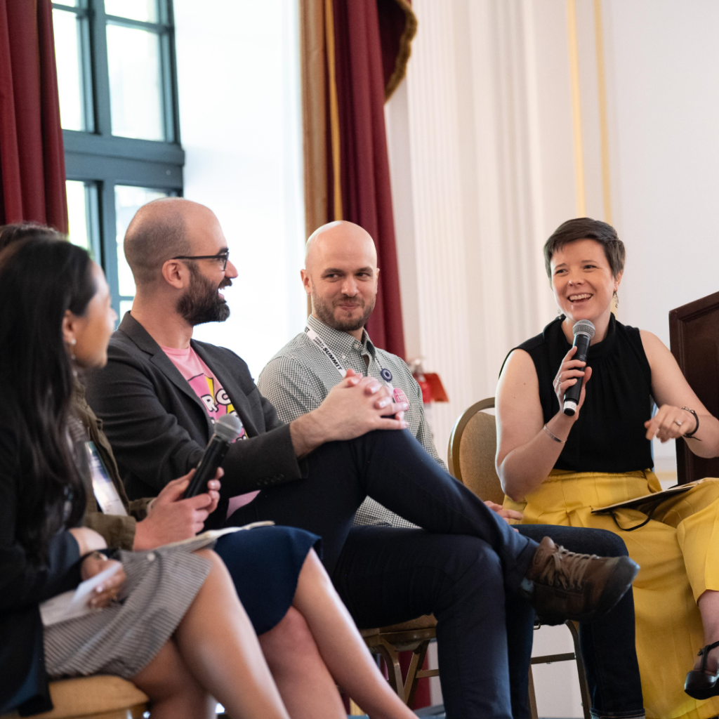 A lively panel discussion at Code for America Summit, with participants smiling and one holding a microphone